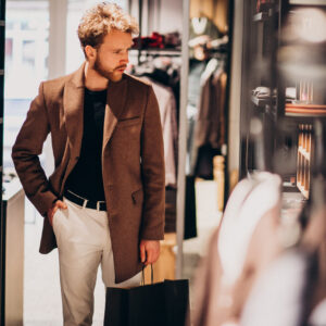 young handsome man choosing cloth at shop